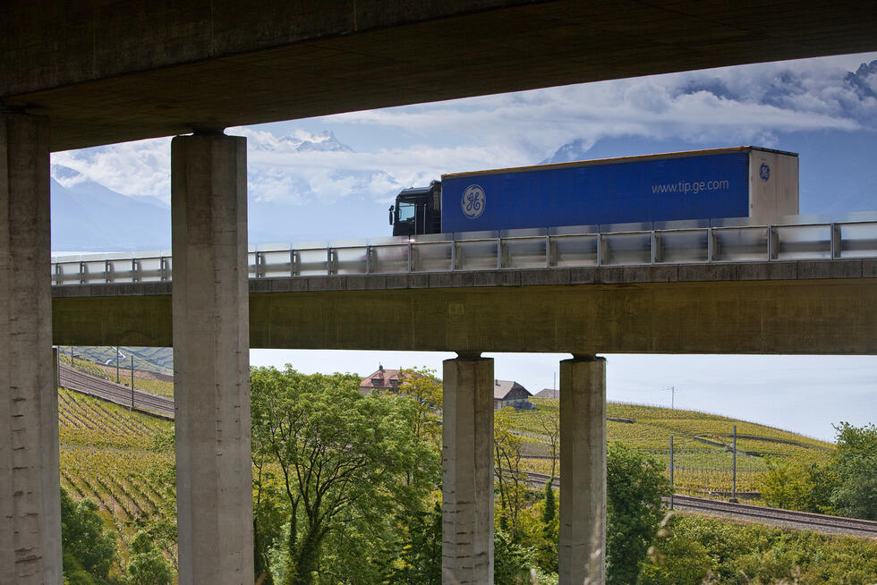 Blue truck driving on a highway bridge