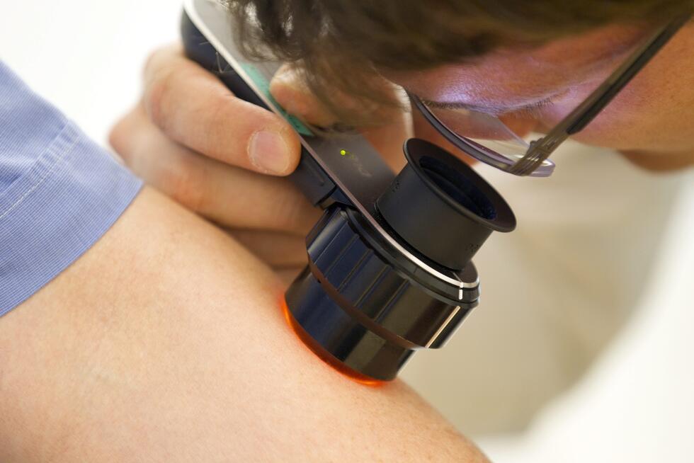 A doctor examines a patient for conspicuous moles