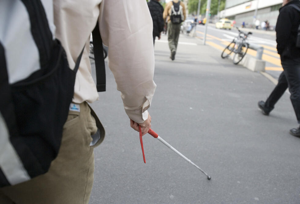 A blind person walks through the city