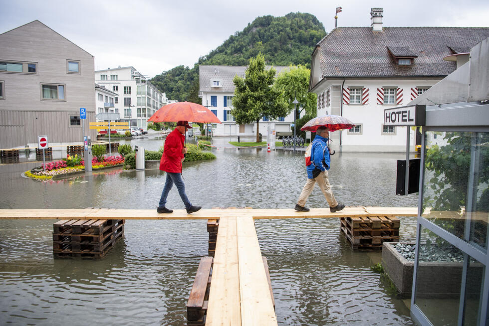 Pedestrians walk on planks across a flooded square in Switzerland.